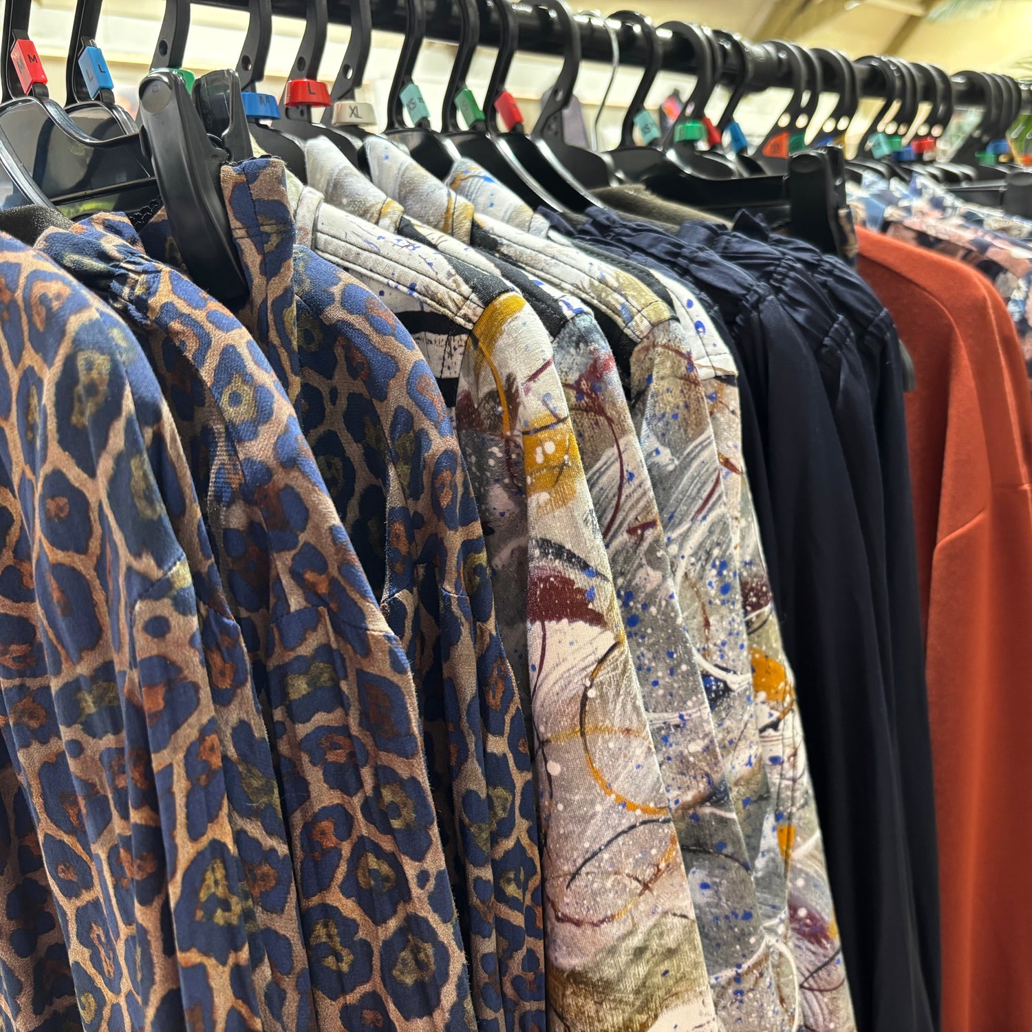 Row of patterned shirts on hangers in a store setting